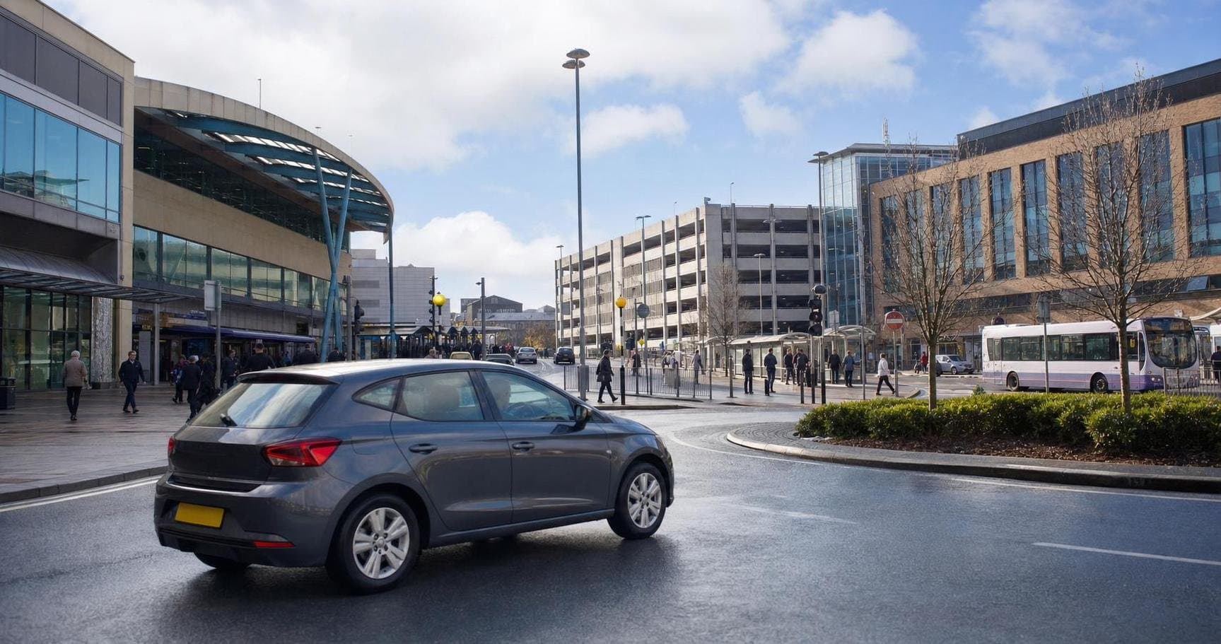 Compact hire car near a town-centre transport and parking area serving Normanton journeys