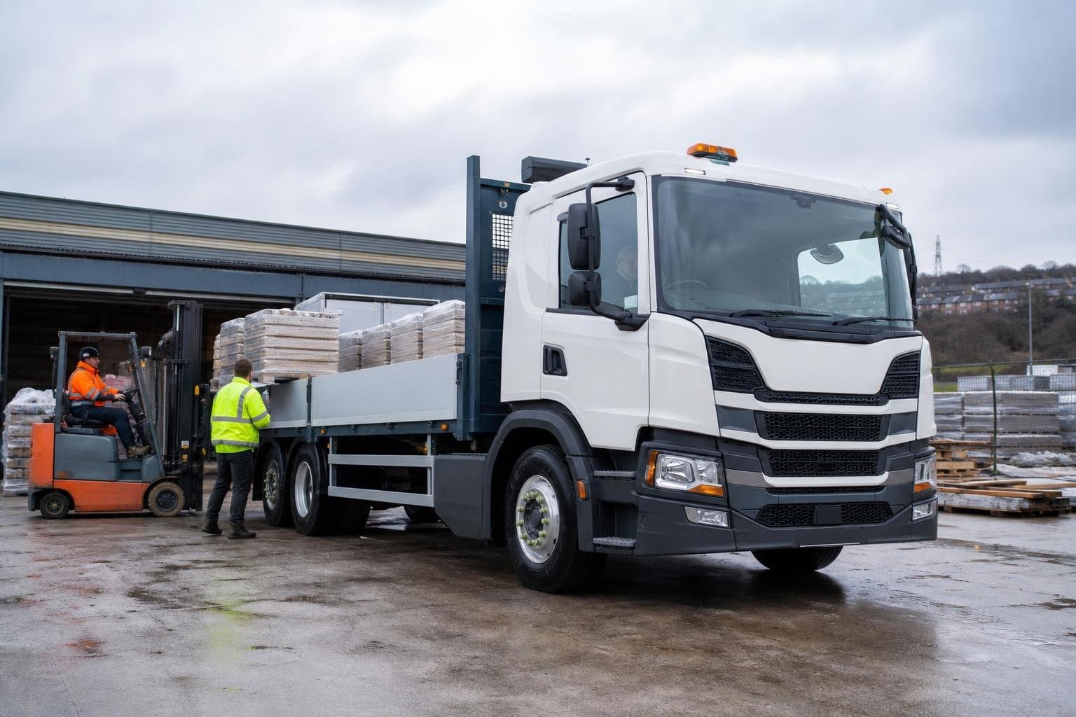 Commercial hire truck in use at an industrial yard with materials being handled nearby